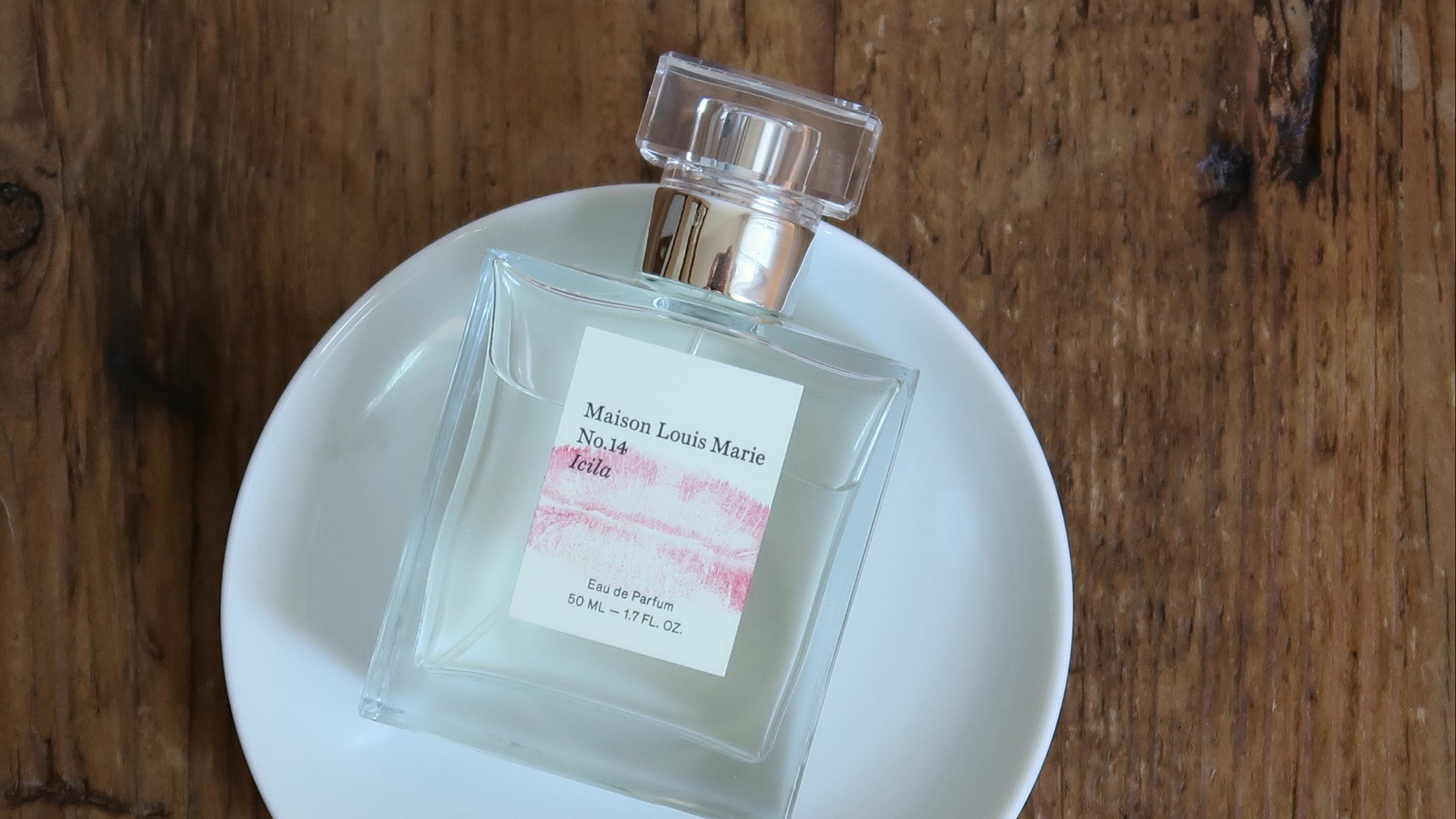 Perfume bottle on a white dish with a wooden background